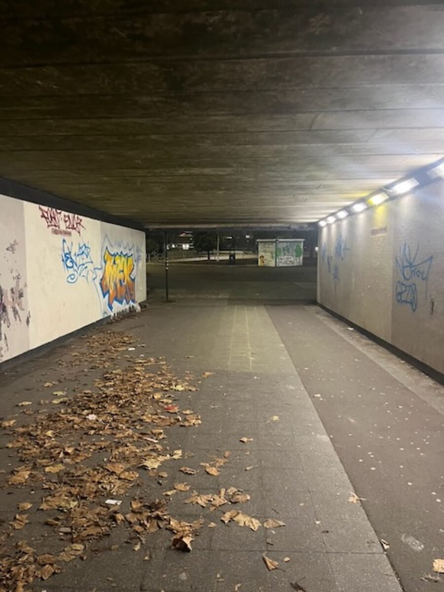 A lit pedestrian subway under a Birmingham ring road, graffiti on the walls